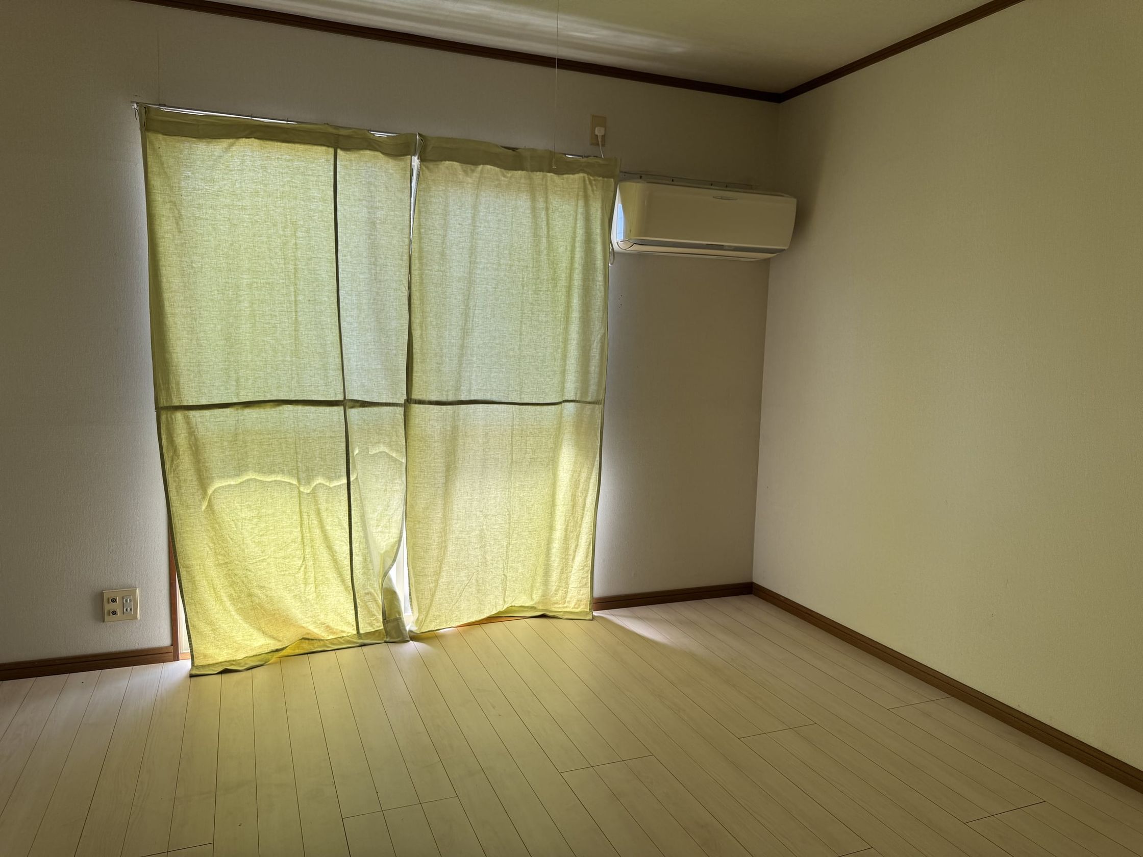 窓にカーテンのある居室。エアコン付き、床はフローリング