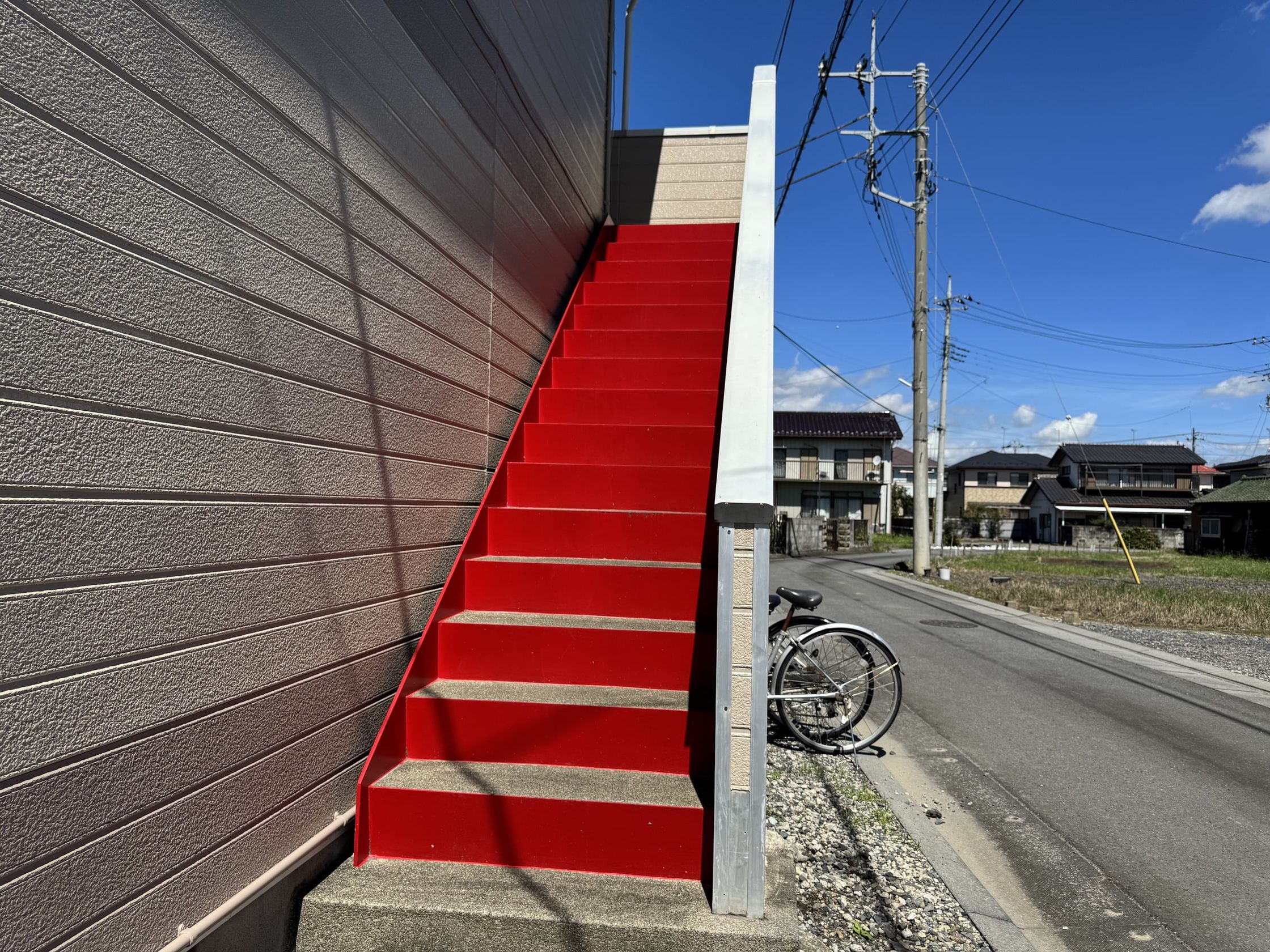 建物の外壁に沿って 2 階へ上がる赤い外階段